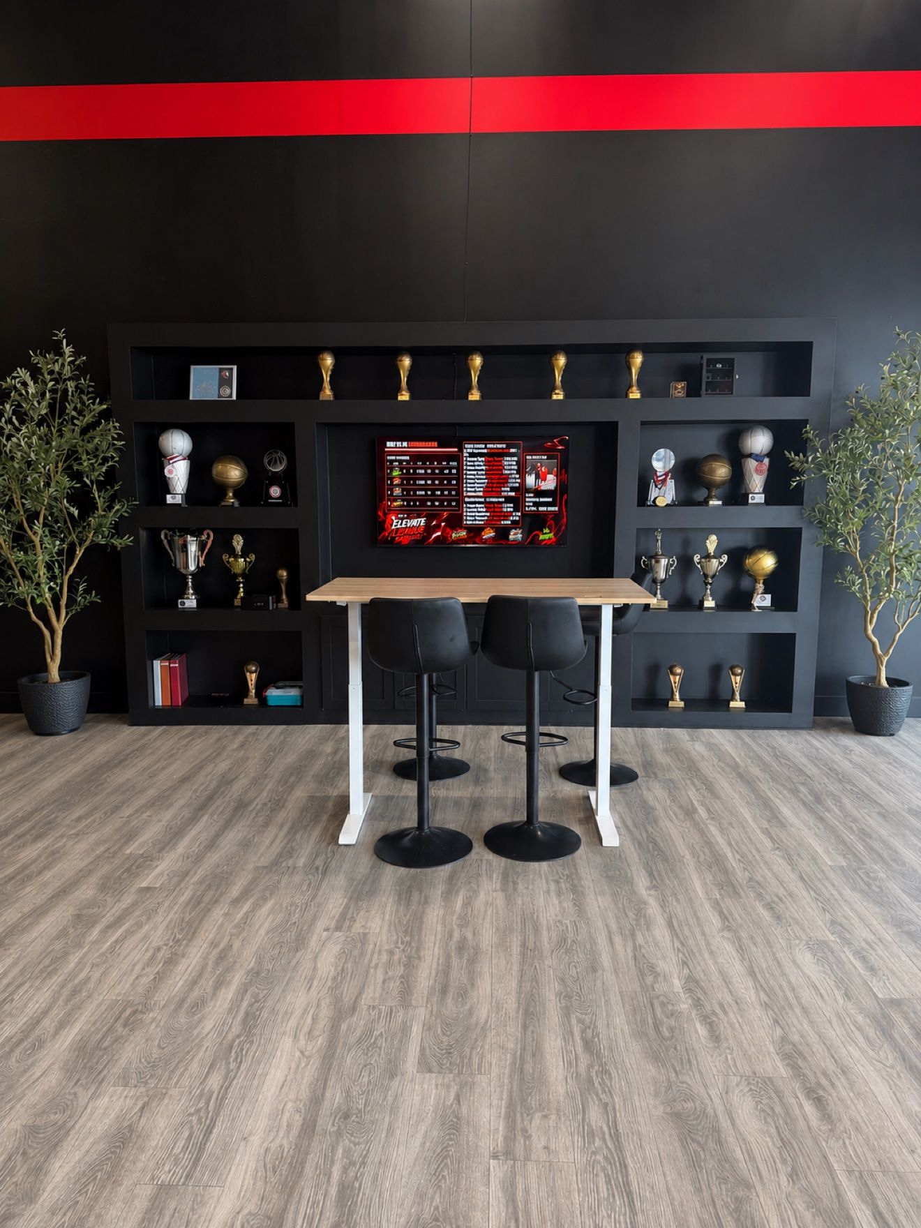 The Next Level lobby with its trophy wall, wall-mounted TV, and high table seating
