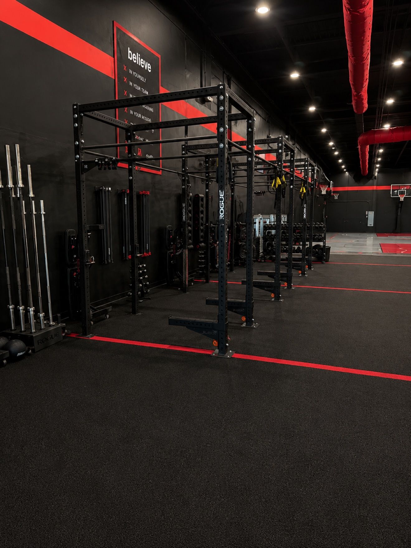 Weight room with Rogue racks, barbells, and the believe wall at Redline Athletics Fort Myers